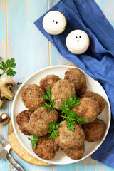 Homemade meatballs with mushrooms on the kitchen wooden table. Top view of a flat lay. Copy space.