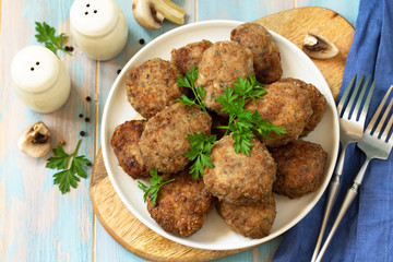 Homemade meatballs with mushrooms on the kitchen wooden table.