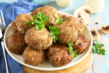 Homemade meatballs with mushrooms on the kitchen wooden table.
