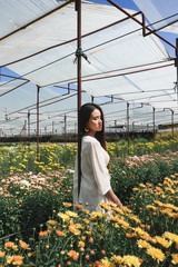 Portrait young beautiful asian woman in white dress relaxing at chrysanthemum flower garden