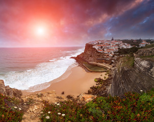 View of Azenhas do Mar at sunset. Big waves Atlantic Ocean crashing into the rocky shore. Dramatic...