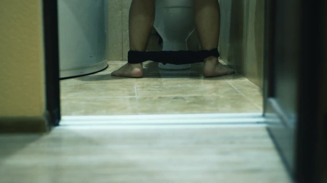 The man hastily runs into the toilet, takes off his pants and pisses