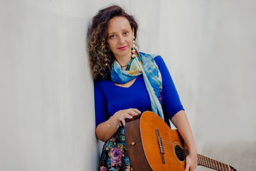 Portrait of young beautiful curly woman posing with guitar