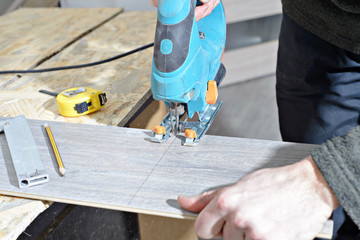 carpenter cutting plank with saw