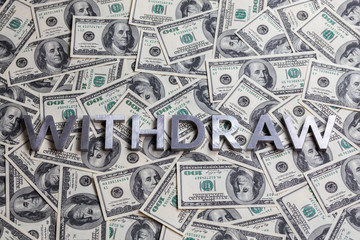 The word WITHDRAW laid with aluminium letters on the US dollar banknotes background - with...