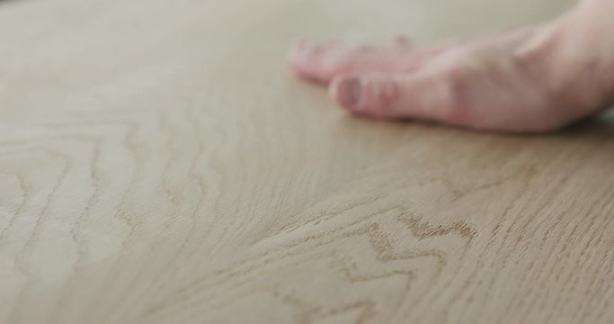Slow motion man hand check quality of oak wood surface