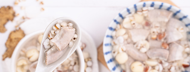 Tasty Four Tonics Herb Flavor Soup, Taiwanese traditional food with herbs, pork intestines on white wooden table, close up, flat lay, top view.