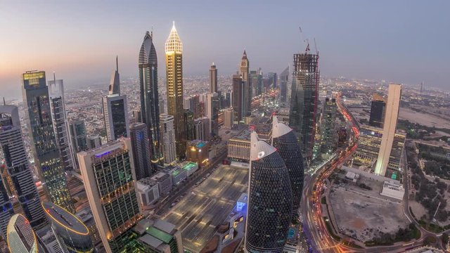 Skyline of the buildings near Sheikh Zayed Road and DIFC aerial day to night transition timelapse in Dubai, UAE. Modern towers and skyscrapers with parking in financial center and downtown after