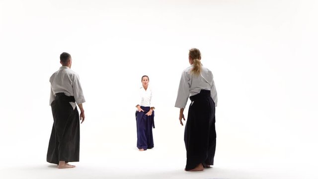Two guys and girl performing aikido techniques, isolated on white.