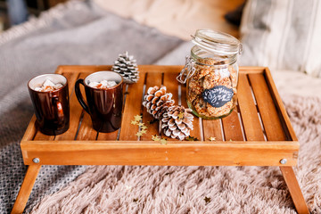Table with a cup on the bed, marshmallow and Christmas cookies, cozy knitted blanket. New Year 2020, flat lay. Christmas composition with a cup tray and a mug