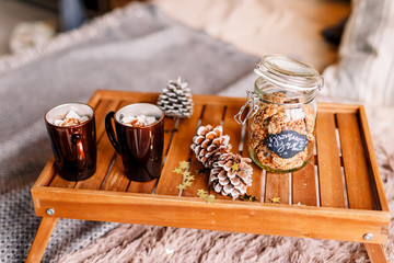 Table with a cup on the bed, marshmallow and Christmas cookies, cozy knitted blanket. New Year 2020, flat lay. Christmas composition with a cup tray and a mug