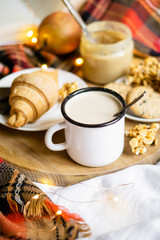 Simple country home breakfast in bed, coffee with milk and homemade pastry on plaid blanket