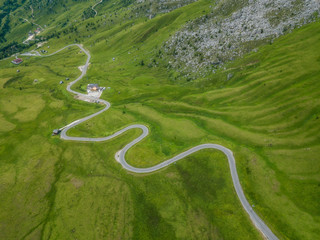 Aerial view of asphalt road, roadway with meadow in Passo Giau, winding road in mountain valley in summer, Dolomites, Italy.