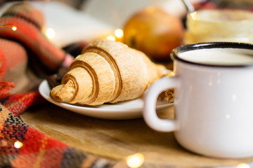 Simple country home breakfast in bed, coffee with milk and homemade pastry on plaid blanket