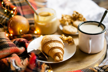 Simple country home breakfast in bed, coffee with milk and homemade pastry on plaid blanket