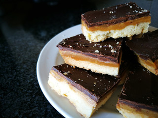 Millionaire's shortbread with chocolate and caramel on a white plate. 