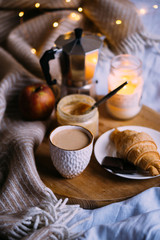 Cozy winter weekend breakfast, coffee and croissant on wooden tray