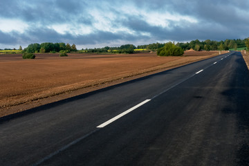 Fototapeta na wymiar New paved road between rural landscapes.