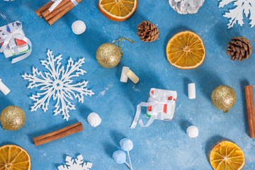 Fototapeta na wymiar Christmas and New Year pattern made of snowflakes,cookies, cinnamon, orange, cones and marshmallows on a blue background with stars. Christmas, winter, new year concept. Flat lay, top view, copy space