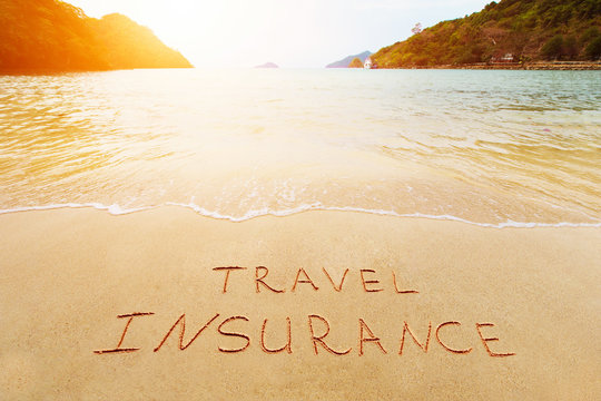 Travel insurance and cover of accidental risk concept. Handwriting drawing on sand. Scenic view on beautiful summer tropical beach of harbor.