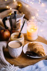 Cozy winter weekend breakfast, coffee and croissant on wooden tray