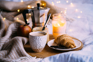 Cozy winter weekend breakfast, coffee and croissant on wooden tray