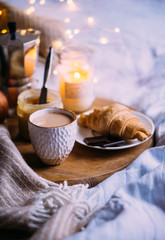 Cozy winter weekend breakfast, coffee and croissant on wooden tray