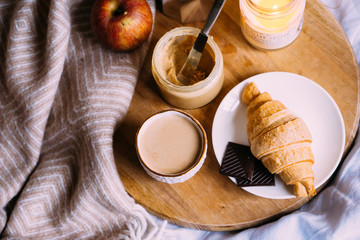 Cozy winter weekend breakfast, coffee and croissant on wooden tray