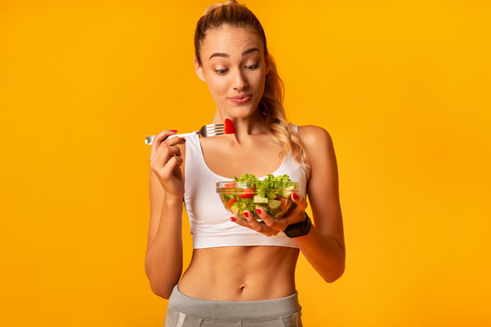 Sporty Woman Eating Vegetable Salad Holding Bowl Standing, Studio Shot