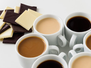 Different coffee in white cups. White and bitter chocolate