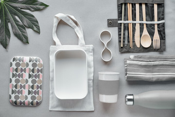 Creative top view, zero waste packed lunch kit, takeaway lunch box set on cotton bag, organizer of bamboo cutlery, bamboo lunch box and reusable cup. Sustainable lifestyle, flat layout on craft paper.