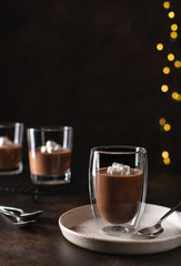dessert panna cotta in a double wall glass, decorated with marshmallows. blurred christmas background