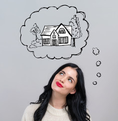 Dreaming of new home with happy young woman on a gray background