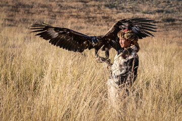 Portrait of a young kazakh eagle hunter with his majestic golden eagle in the steppe. Ulgii, Mongolia.