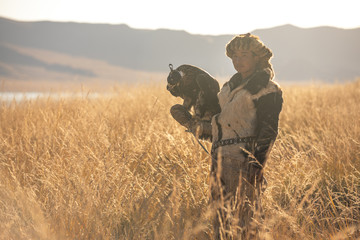 Portrait of a young kazakh eagle hunter with his majestic golden eagle in the steppe. Ulgii,...