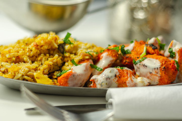 Pieces of cooked marinated chicken breast in an onion and tomato sauce with yogurt and mint and crispy fried onions layered with spiced basmati rice