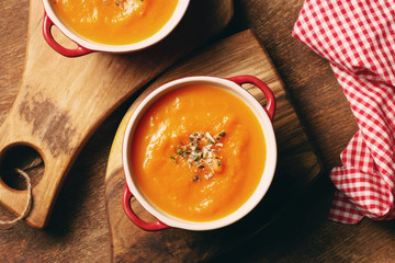 Pumpkin cream soup in small sauce pan with pumpkin seeds and thyme leaves