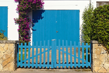 Residential blue garage door with a blue fence in the front
