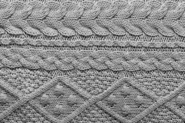 Gray knit fabric background with horizontal Irish cable pattern and rhombs, wool texture in soft tones