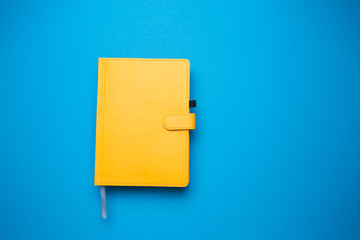 Diary of yellow color on a blue isolated background close-up.