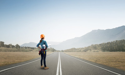 Young woman in safety helmet standing on road