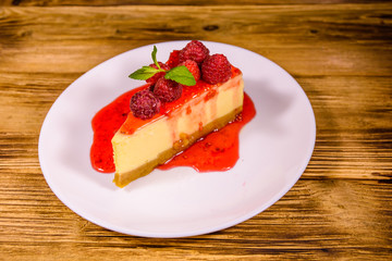 White plate with cheesecake New York, leaf of mint and raspberries on wooden table