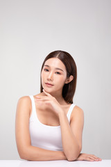 Fototapeta premium Beautiful Young Asian Woman Looking While Touching Chin feeling so happy and cheerful with healthy Clean and Fresh skin,isolated on gray background,Beauty Cosmetics Concept