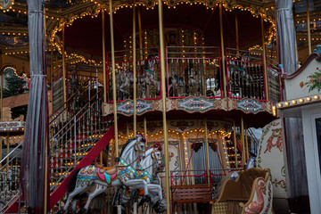 Carousel with horses. Ornate vintage carousel with toy horses and shiny golden lights. Circle merry-go-round at funfair in Europe. Fairytale retro style roundabout swings. Childhood concept