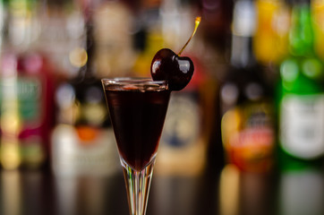 Cherry liqueur and juicy ripe cherries on the table in the bar, an elegant serving of sweet drink in the restaurant