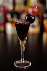 Cherry liqueur and juicy ripe cherries on the table in the bar, an elegant serving of sweet drink in the restaurant