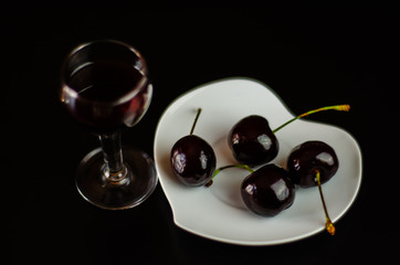Cherry liqueur and juicy ripe cherries on the table in the bar, an elegant serving of sweet drink in the restaurant