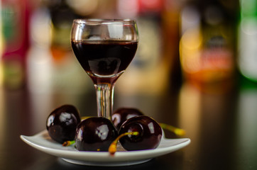 Cherry liqueur and juicy ripe cherries on the table in the bar, an elegant serving of sweet drink in the restaurant