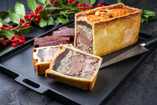 Traditional French Pate en croute with goose meat and liver offered with quince cheese as closeup on a modern design cast iron tray