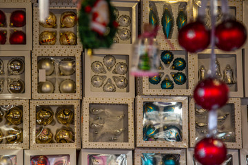 A variety of boxes with Christmas baubles with hanging Christmas baubles in a blurry foreground on a German Christmas market